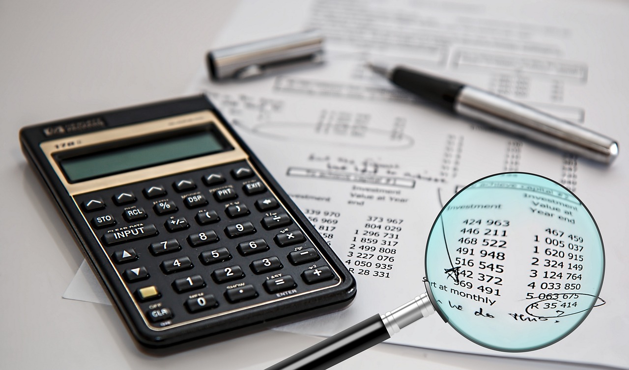 Close-up of a calculator, pen, financial documents, and magnifying glass highlighting figures — symbolizing an IRS tax audit and financial review.